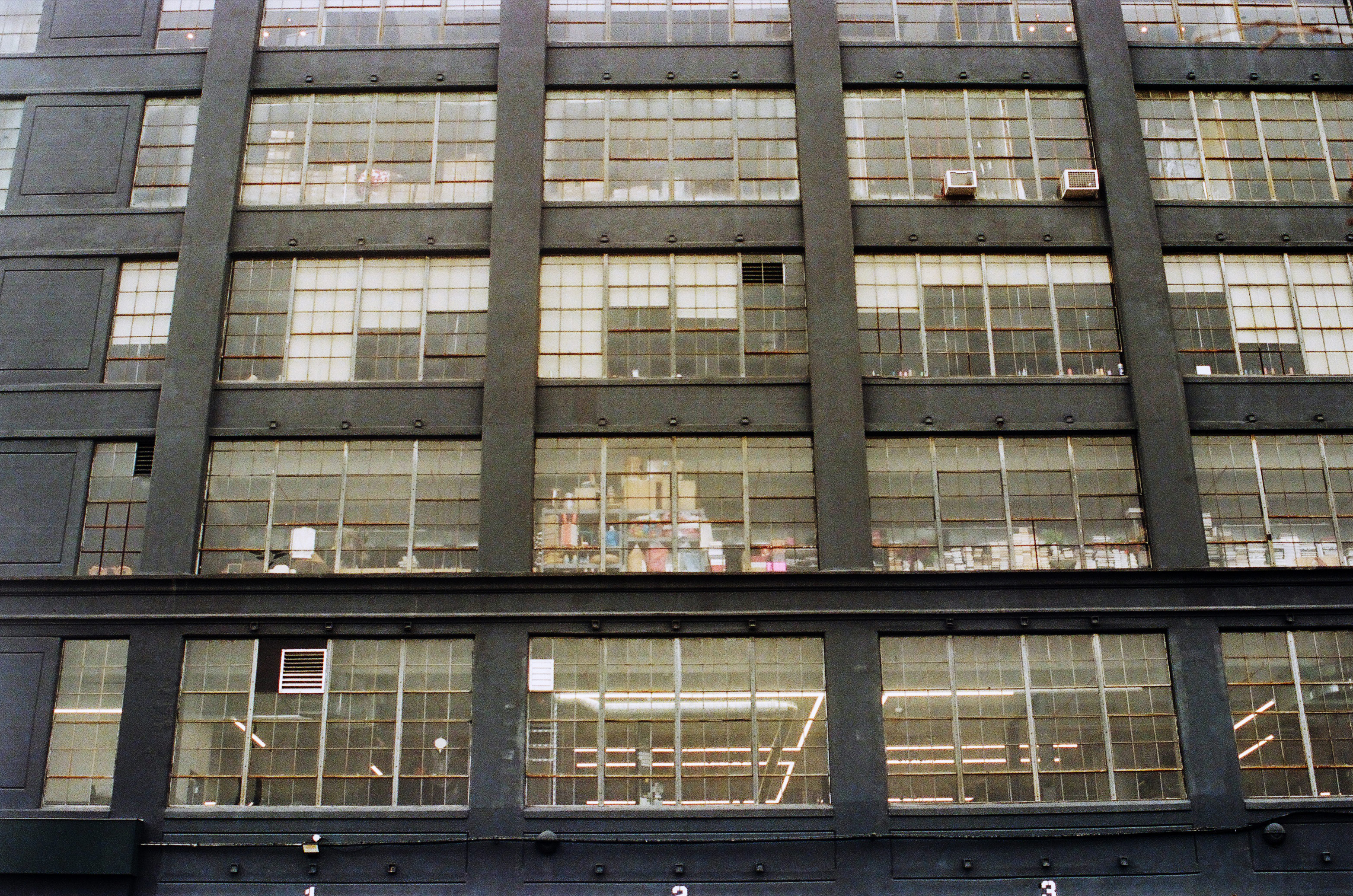 a large black industrial building shows a wall of windws over multiple stories with lots of stuff inside
