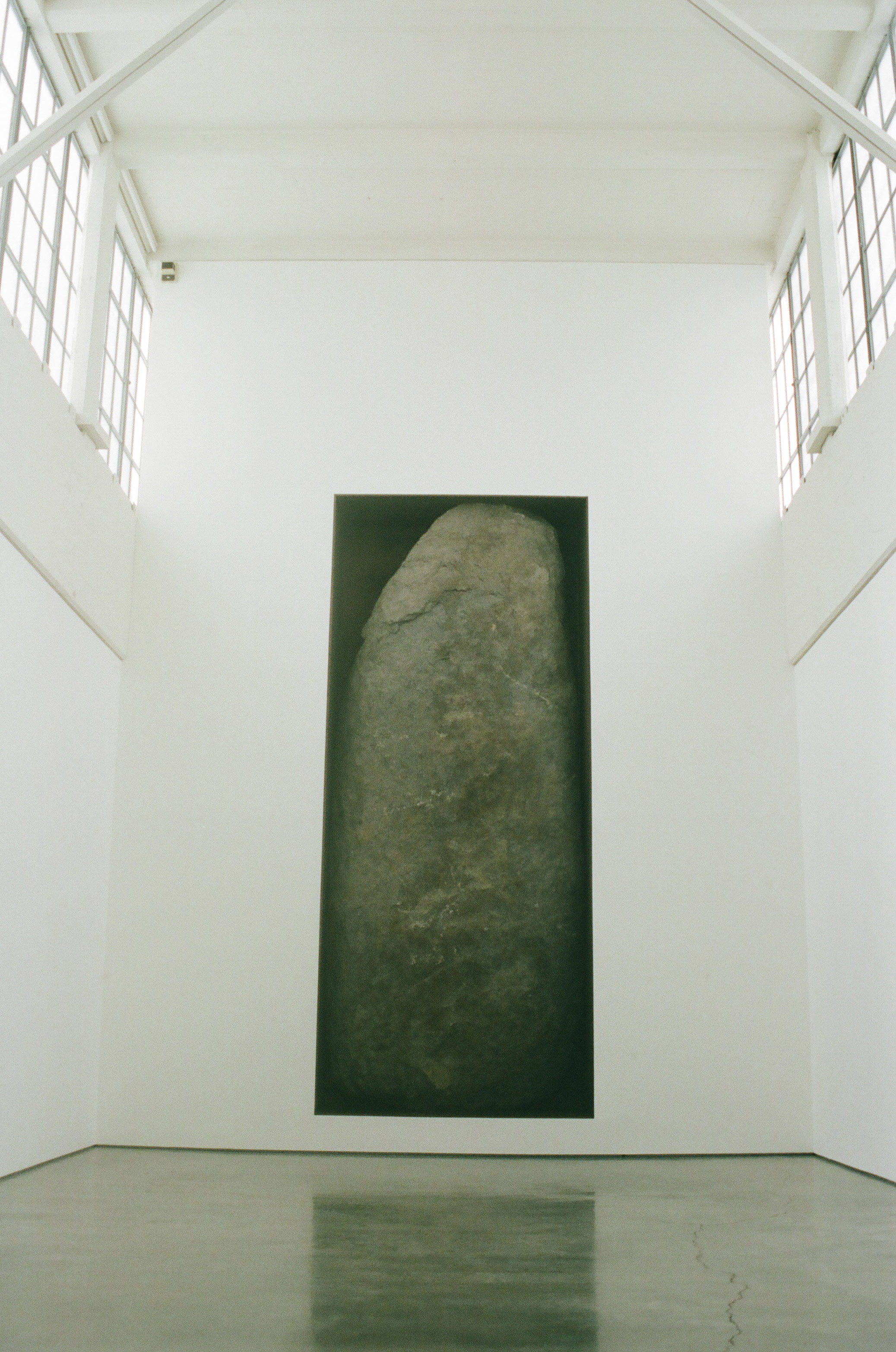 a view of Michael Heizer's giant boulder art Negative Megalith #5 inside a white gallery room