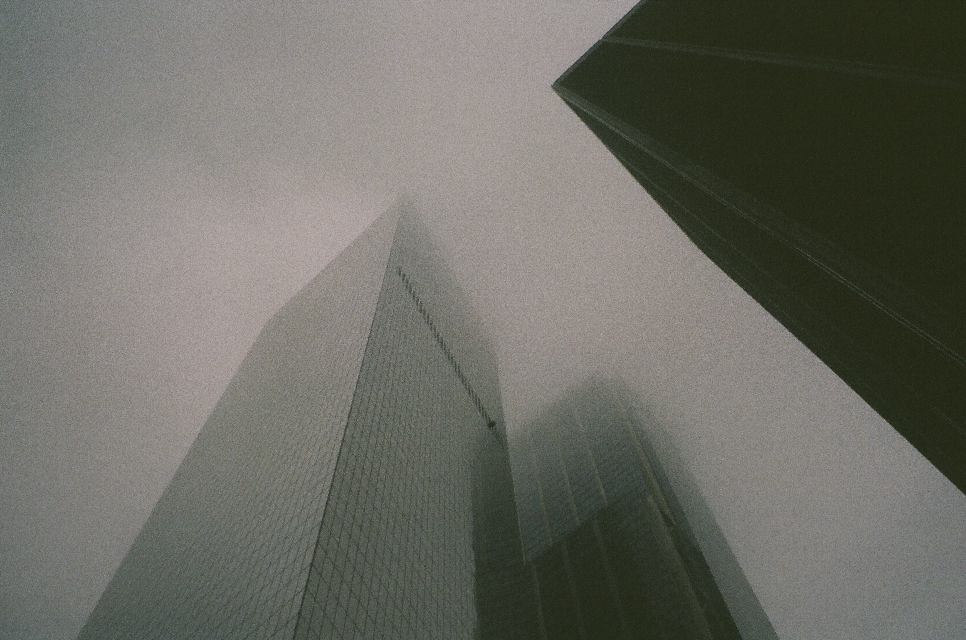 Looking upward at a series of skyskrapers fading into the foggy sky