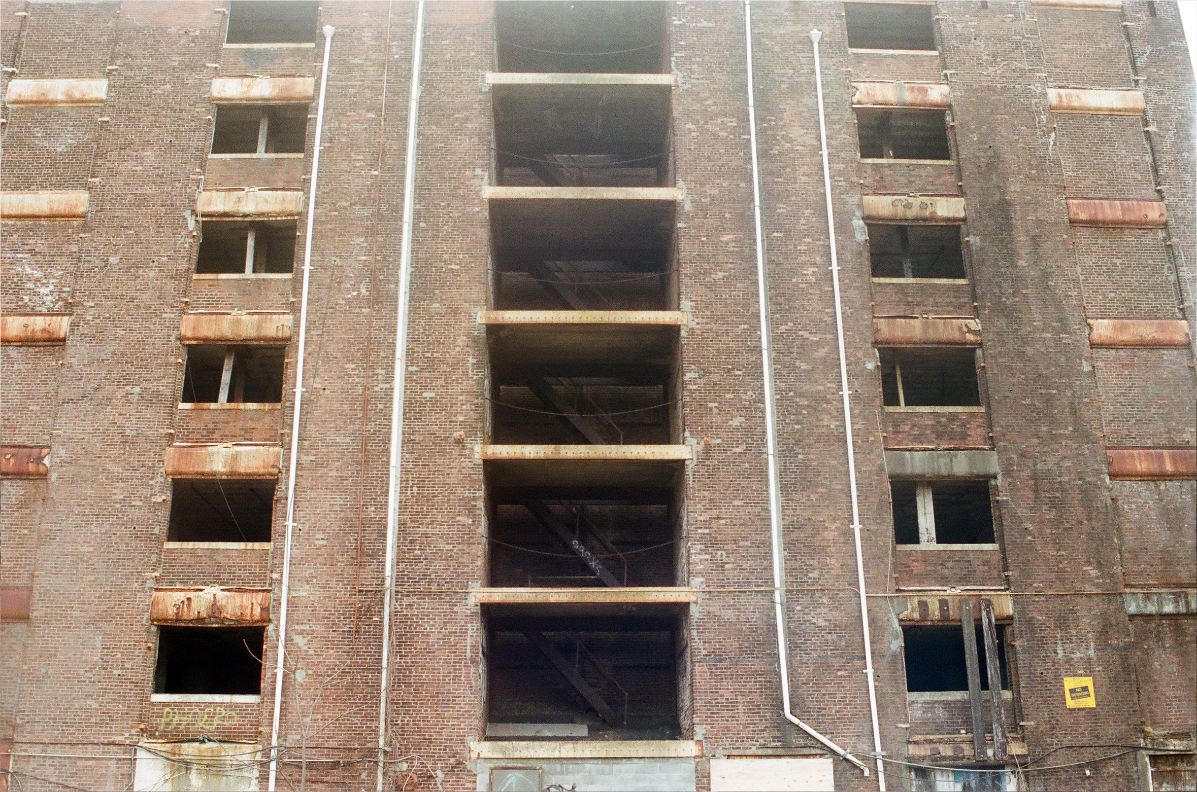 an abandoned brick building with an exposed stairwell takes up the entire composition